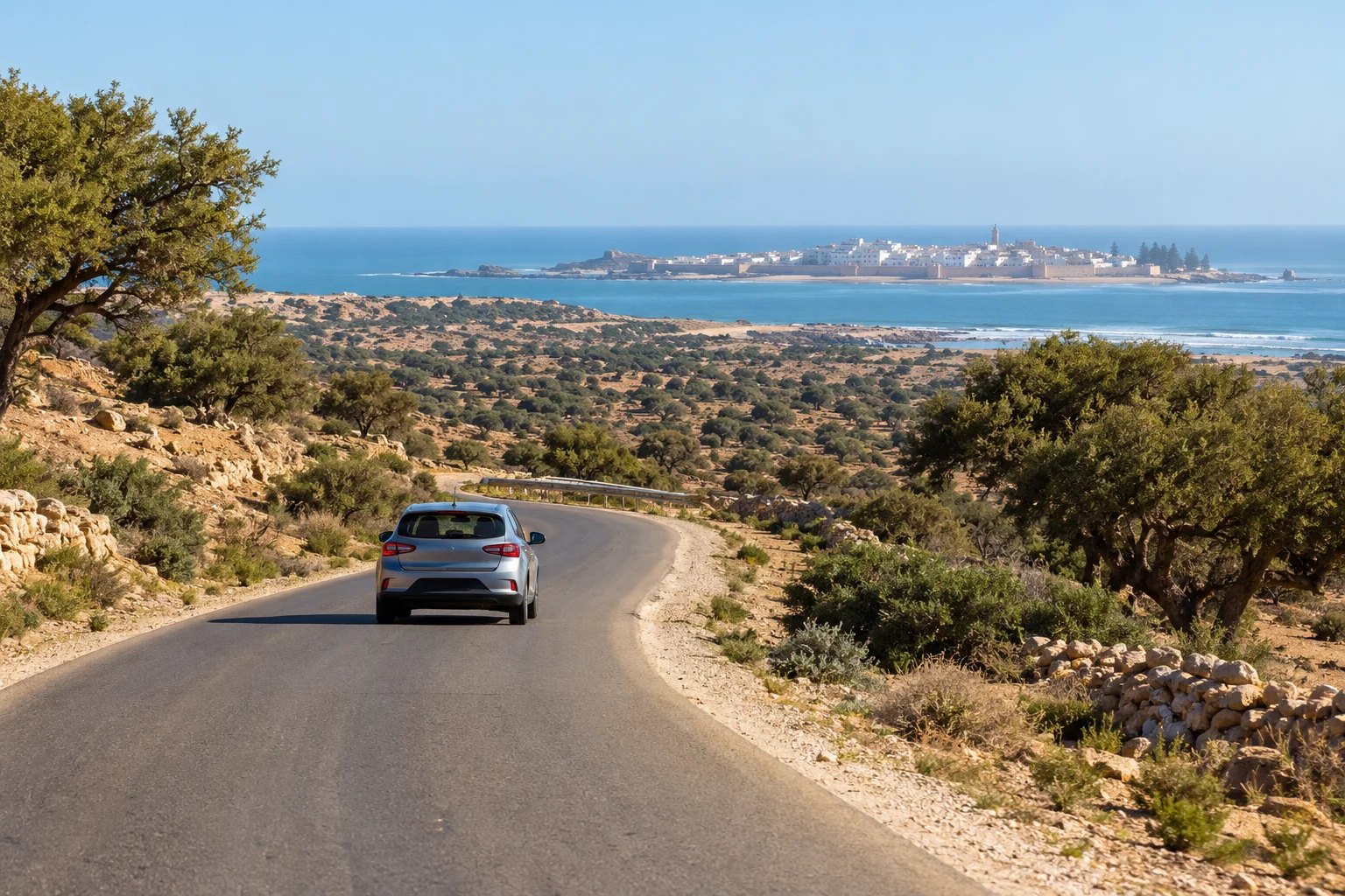 Kompakter Mietwagen auf der Straße R207 durch Arganen-Landschaft auf dem Weg nach Essaouira. Flughafen Marrakesch nach Essaouira